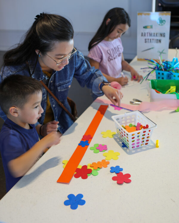 Two children and an adult at a table with a art supplies