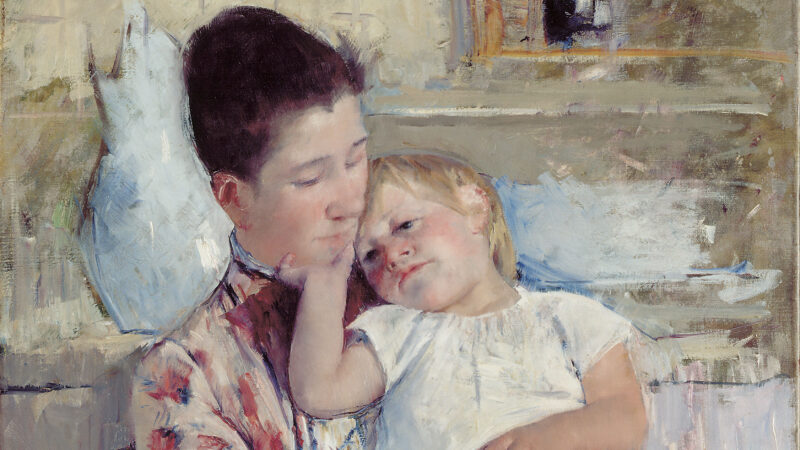 A woman in a flowered dress holds a child. There is a blue vase and washbasin behind them in this painting by Mary Cassatt