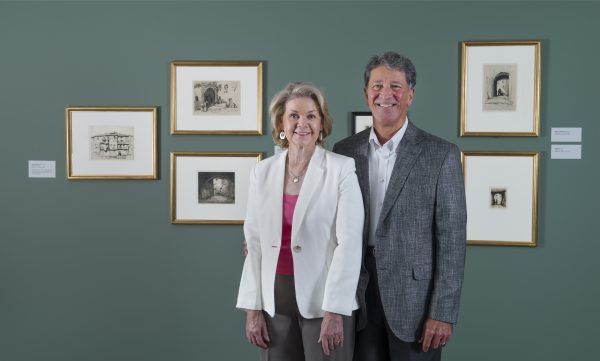 Interior view of two people standing the galleries looking at the camera