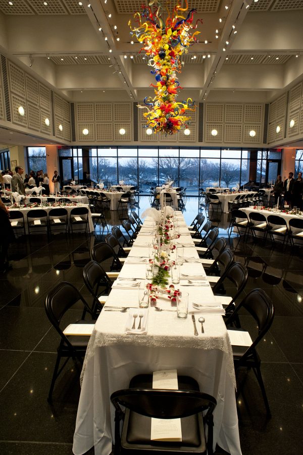 Interior view at night of tables and chairs set up in the S. Jim and Darla Farha Great Hall
