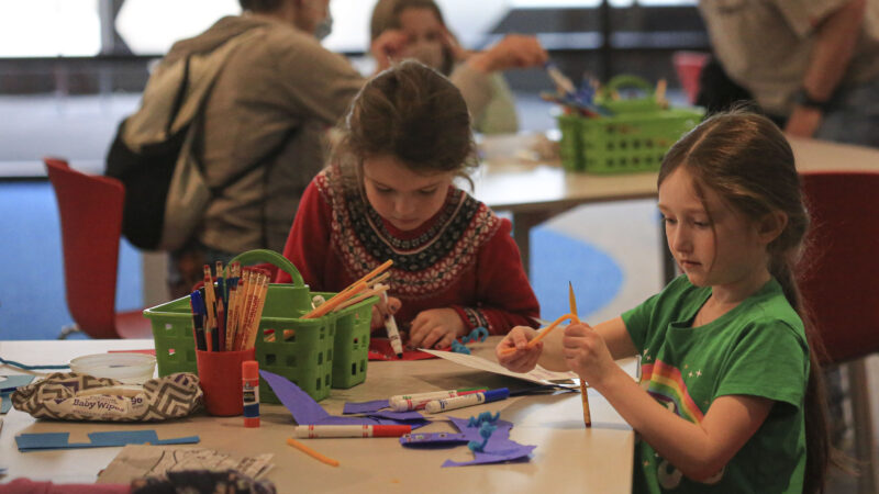 Two young girls at a talbe with art supplies.