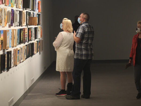 Interior image of the Foot in the Door galleries with multiple visitors looking at paintings on the wall