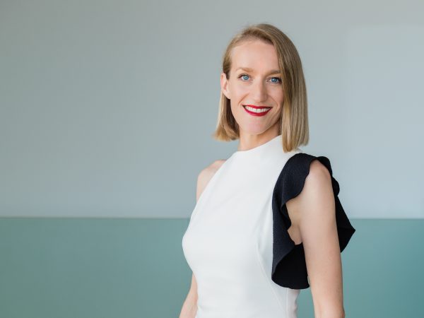 Photo of a white women with above-the-shoulder length straight blonde hair looking to the left and wearing a white and black blouse