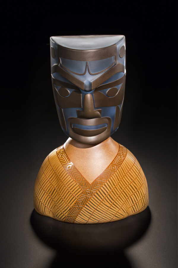 Glass sculpture of a totem-style head in dark brown on a lighter brown base.