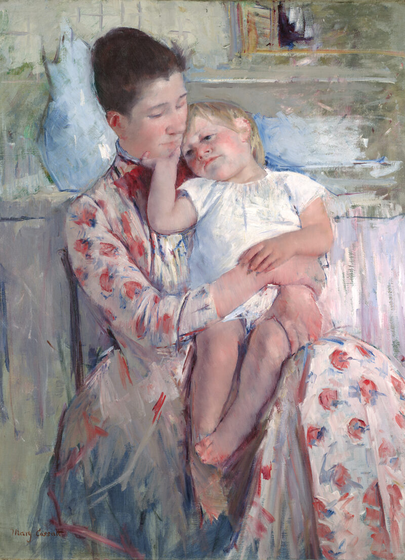 A woman in a flowered dress holds a child. There is a blue vase and wash basin behind her.