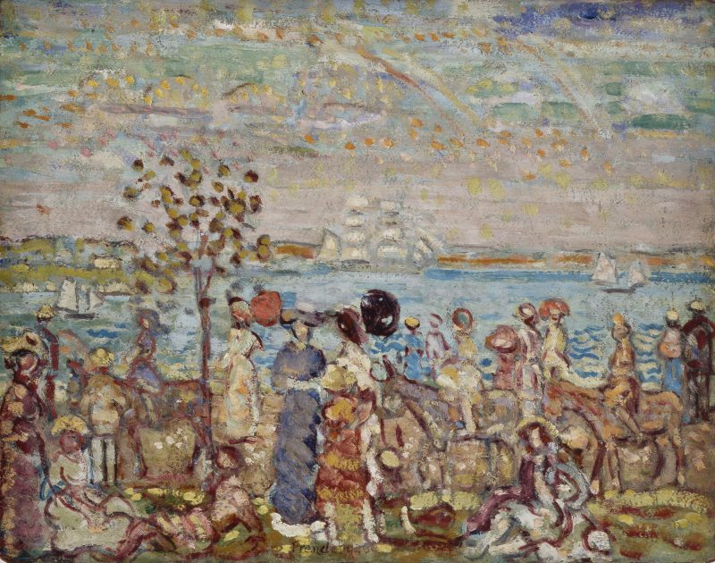 A scene of a crowd in a park with water and boats in the background.