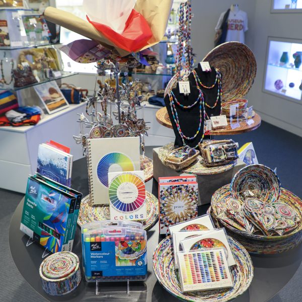 Display of colorful merchandise from the Museum Store including necklaces, notecards, baskets, markers and Christmas tree ornaments