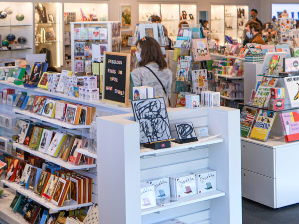 Interior photo of the Museum Store showing six aisles of merchandise with two female shoppers in the foreground