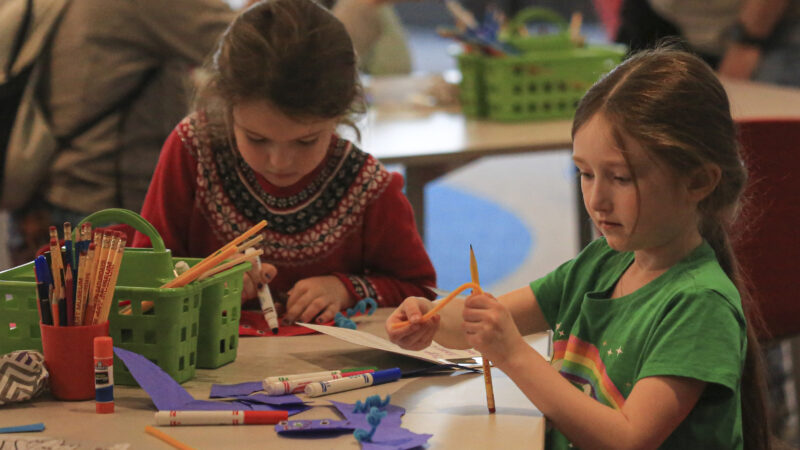 Girls sitting at a table with art supplies.