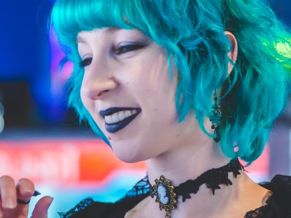 Photo of Veronica Dowty, artist for Sketching in the Galleries. She is wearing a black dress and has turquoise-blue hair.