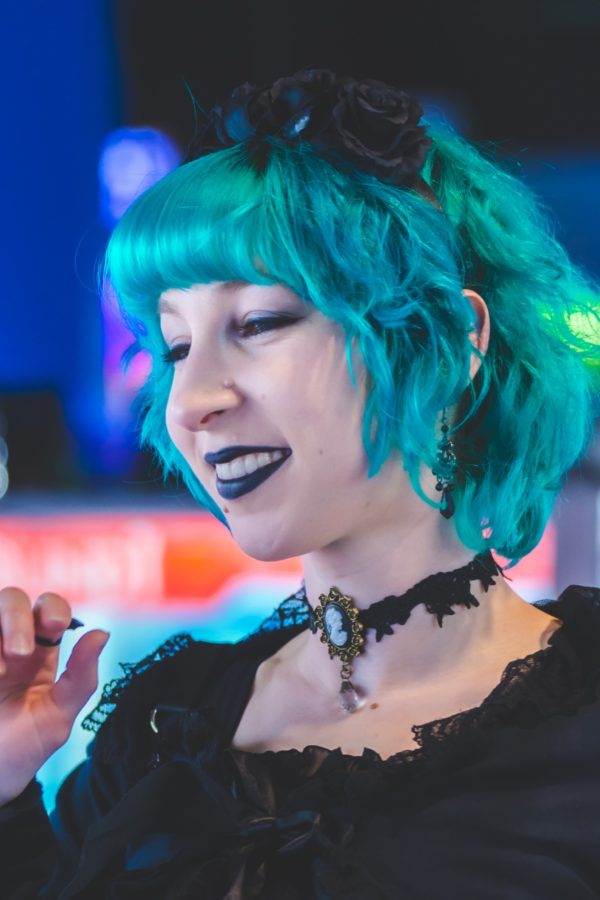Photo of Veronica Dowty, artist for Sketching in the Galleries. She is wearing a black dress and has turquoise-blue hair.