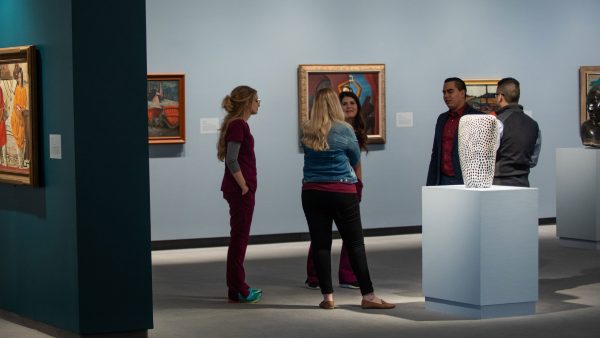 Photo of five members of Wichita Chamber of Commerce's W group standing in the Storytelling exhibition and talking with one another