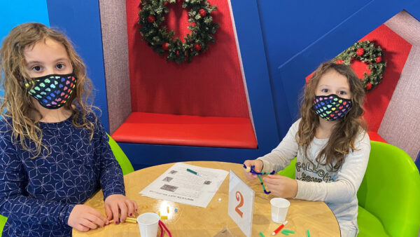 Two young girls sitting at a table with art supplies in front of them