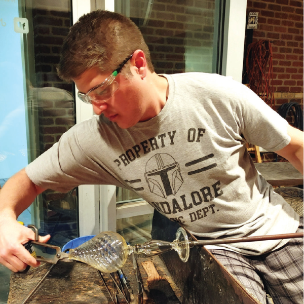 Aaron Jasso using glass blowing techniques to create a glass object.