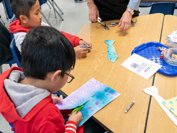 Two children doing arts and crafts by cutting out paper